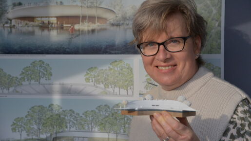 Festspiele-Mitarbeiterin Kerstin Gradert hält das Modell in Händen, das Vorbild sein soll für den Neubau der Tribüne am Großen Eutiner See. Die Pläne sind jetzt im Gastro-Pavillon der Festspiele ausgestellt. Foto: EFS